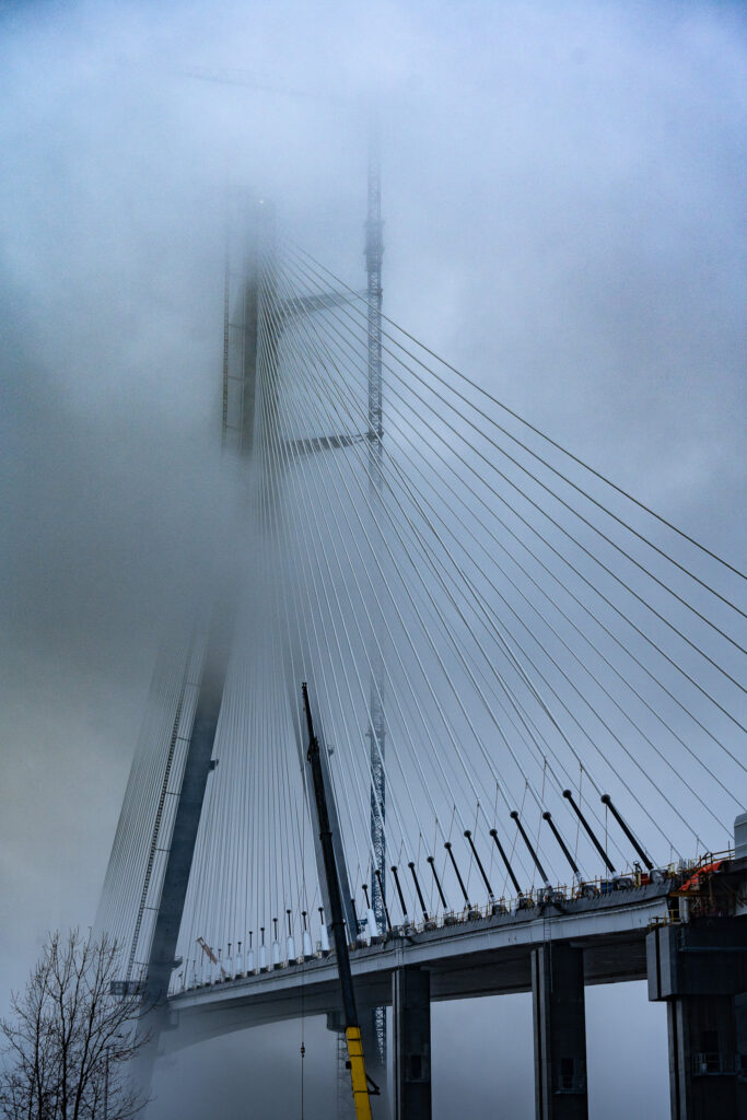 Mast of bridge surrounded by clouds