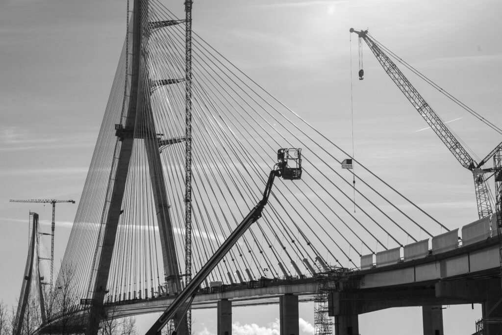 black and white photo of bridge construction equipment like crane and boom lift
