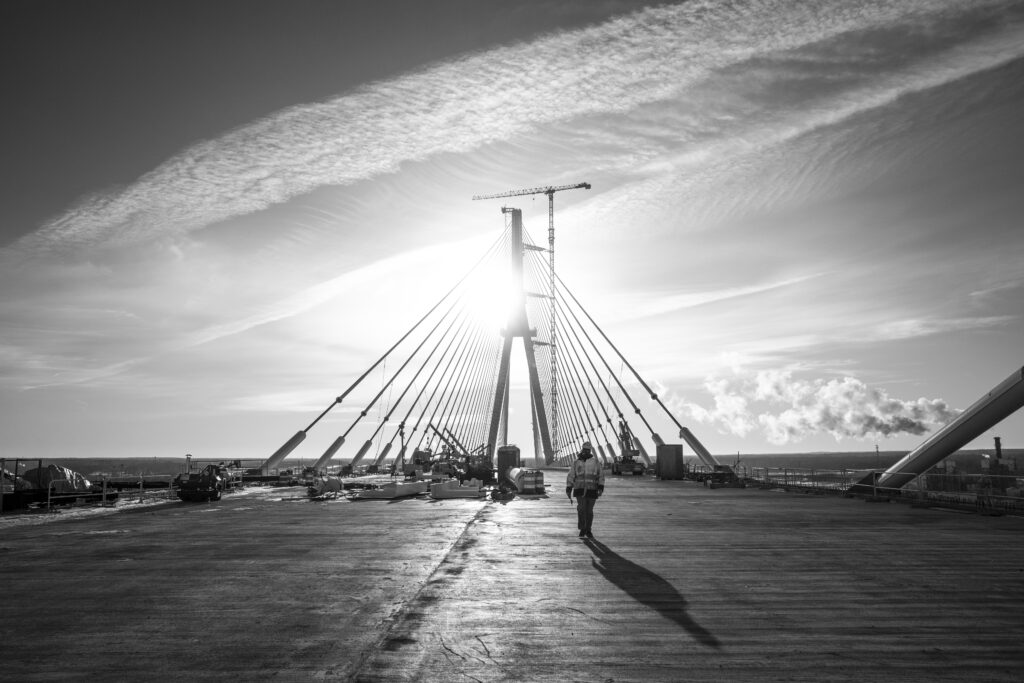 Black and white image of construction worker walking across bridge span