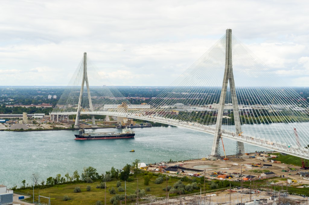 Image of the Gordie Howe International Bridge with a frater boat travelling on the Detroit River